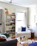 Cozy living room with a white armchair, fireplace, bookshelf, and colorful cushions.