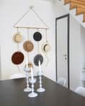 Staircase with wooden steps, wall-mounted hats, white candlesticks on table, and a potted plant.