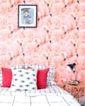 A single bed with mattress, covered in checkered bedsheet, sits against a floor-to-ceiling photo of swans