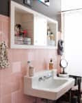 Bathroom with pink tiles, white sink, mirrored cabinet, polka dot towel, and shower curtain.