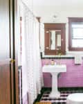 Bathroom with pink subway tiles, pedestal sink, white shower curtain, and framed art on walls.