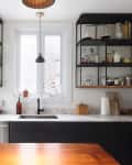 Modern kitchen with open shelving, glass jars, a wooden countertop, and a central window above the sink.