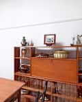 Mid-century dining room with wooden table, vintage dishware, and decorative mirror.
