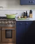 Navy blue kitchen with lime green dutch oven on a stove