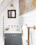 A sun-filled bathroom with white tile and gold hardware.