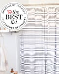 White shower with striped black and white curtain and gold shower caddy. Seal in upper left corner reads "Apartment Therapy the Best List 2023 Shower Organizers"