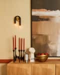 wood credenza with candles, lamp, l'objets. abstract print on wall behind