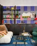 Colorful room in with a mix of deco and memphis group style. Patterned wallpaper, colorful abstract art prints on wall. Geometric, bright decor accents
