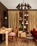 modern archival style room with yellow floral long curtains, deep red velvet sofa, artifacts, a desk, abstract art prints