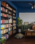 Cozy reading nook with blue walls, green sofa, bookshelves, and mustard armchairs.