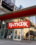 Storefront of TJ Maxx with glass facade and red awning, displaying clothing and home goods inside.