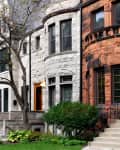 Historic stone townhouses with arched windows, iron railings, and a tree-lined sidewalk.
