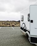 Camper van parked on an empty lot with a rocky landscape in the background.