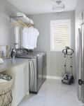 A tidy laundry room with patterned wallpaper and stainless steel appliances