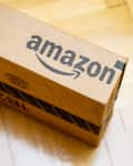 Cardboard box with Amazon logo on a wooden floor.
