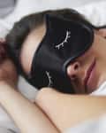 Portrait of young woman with sleep mask in bed.