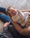 Overhead view of parents with newborn daughter sitting on bed at home