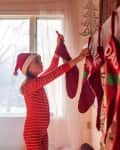 Girl hanging Christmas stockings on a fireplace