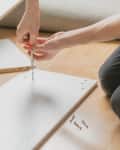 close up man assembling new particle board furniture with a screwdriver