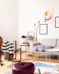 living room decorated with grey sofa, armchair, retro commode and posters on the wall