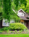 A quaint fairytale cottage, covered by lush plant life and flowers, in the Rose Garden at Stanley Park, Vancouver, British Columbia, Canada.