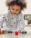 Happy smiling toddler girl playing with toy cars and animal figures in the kitchen