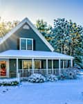 Morning sun rises behind a single family home on Cape Cod decorated for Christmas after a light overnight snowfall
