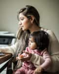 Mother multi-tasking with infant daughter in home office