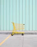 Yellow Shopping Cart On Footpath Against Wall