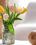 Aroma oil diffuser lamp on the table on a blurred background with a beautiful spring bouquet of tulips.