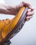 Closeup of Male Hands with Polishing Brush for Tan Brogue Derby Boots. Horizontal Image Orientation