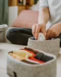 Woman organizing clothes in wardrobe, putting shirts in boxes. Concept of order, minimalist closet, japanese t-shirt folding system and clothes storage