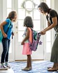 Mother packing daughters backpacks for school