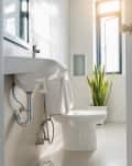White bathroom door that overlooks the sink and toilet lit by the window.