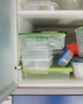 Kitchen cabinet filled with various plastic food storage containers with colorful lids.