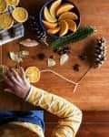 Childs hands putting together dried orange garland for Christmas