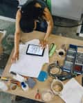 High angle view of craftswoman using digital tablet on table in diy craft workshop