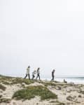 Family walking along beach against clear sky