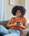 Woman using a cellphone while relaxing on a sofa at home