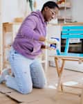 Young woman is painting a chair at home