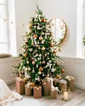 White and spacious domestic living room decorated with Christmas fir tree and pastel holiday decor. Festive craft gift boxes and wrapped presents for family and friends. Cozy celebrations at home