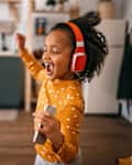 Cheerful girl listening music and dancing at home
