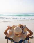 Summer beach travel vacation concept, Traveler woman with hat and dressing bikini relax on chair beach.