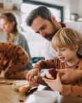 Cheerful parents with small children preparing food at home together.