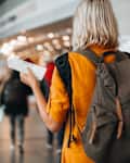 A woman at the airport holding a passport with a boarding pass