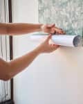 person installing peel and stick wallpaper to wall