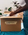 Woman packing donation box on bed at home
