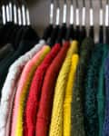Brightly coloured random wool sweaters hung up in a closet