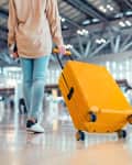 Traveler passenger walking with a yellow suitcase at the modern Airport Terminal