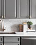 A grey kitchen with a gold faucet and marble subway tile